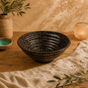 Zwart-bruin gespikkelde keramische kom van 20 cm op een houten tafel met warme natuurlijke styling.
