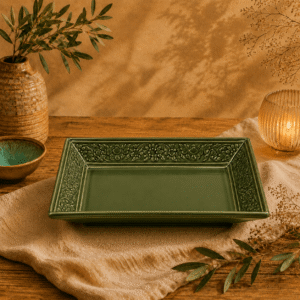 Groene rechthoekige keramische schaal met bloemreliëf gestyled op een warme houten tafel met natuurlijke decoratie.