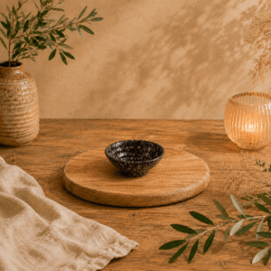Diep zwart-bruin gespikkeld keramisch schaaltje van 8 cm op een houten serveerplank in een warme natuurlijke setting.