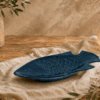 Blauw keramisch visbord van 36 cm in visvorm op een houten tafel met warme natuurlijke sfeerdecoratie.