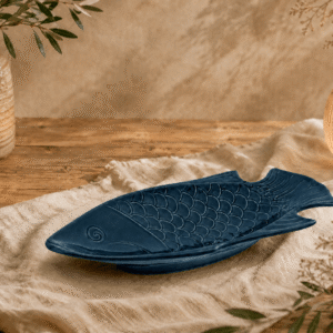 Blauw keramisch visbord van 36 cm in visvorm op een houten tafel met warme natuurlijke sfeerdecoratie.