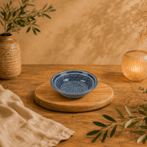 Handgemaakt keramisch rond Lanna schaaltje met visreliëf in blauw op houten tafel in warme sfeervolle setting