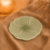 Groen bloembord Lotus van 20 cm, sfeervol gepresenteerd op beige stof met warme verlichting.