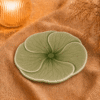 Groen bloembord Lotus van 22 cm, sfeervol gepresenteerd op beige stof met warme verlichting.