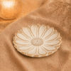 Créme-bruin bloemenschaaltje van 13 cm, sfeervol gepresenteerd op beige textiel bij warme verlichting en droogbloemen.
