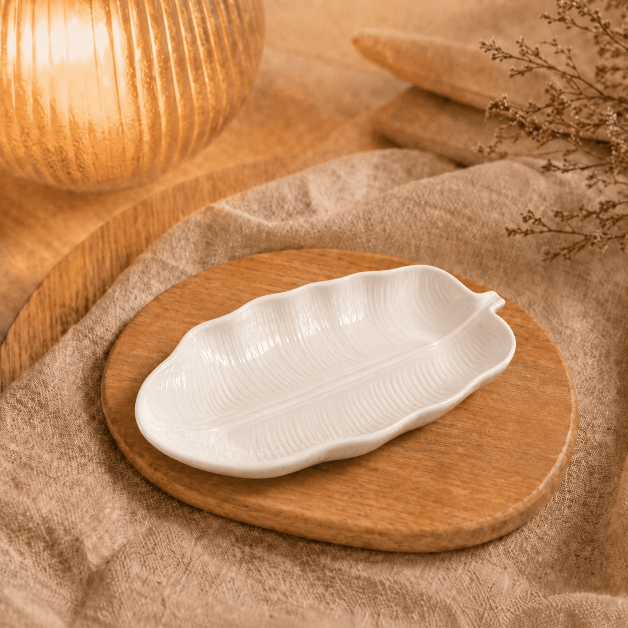 Witte schaal in de vorm van een bananenblad met reliëf, sfeervol gepresenteerd op een houten plank.