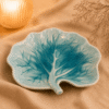 Turquoise serveerbord Lotus van 23,5 cm in bladvorm met sierlijk nervenpatroon, sfeervol gepresenteerd.