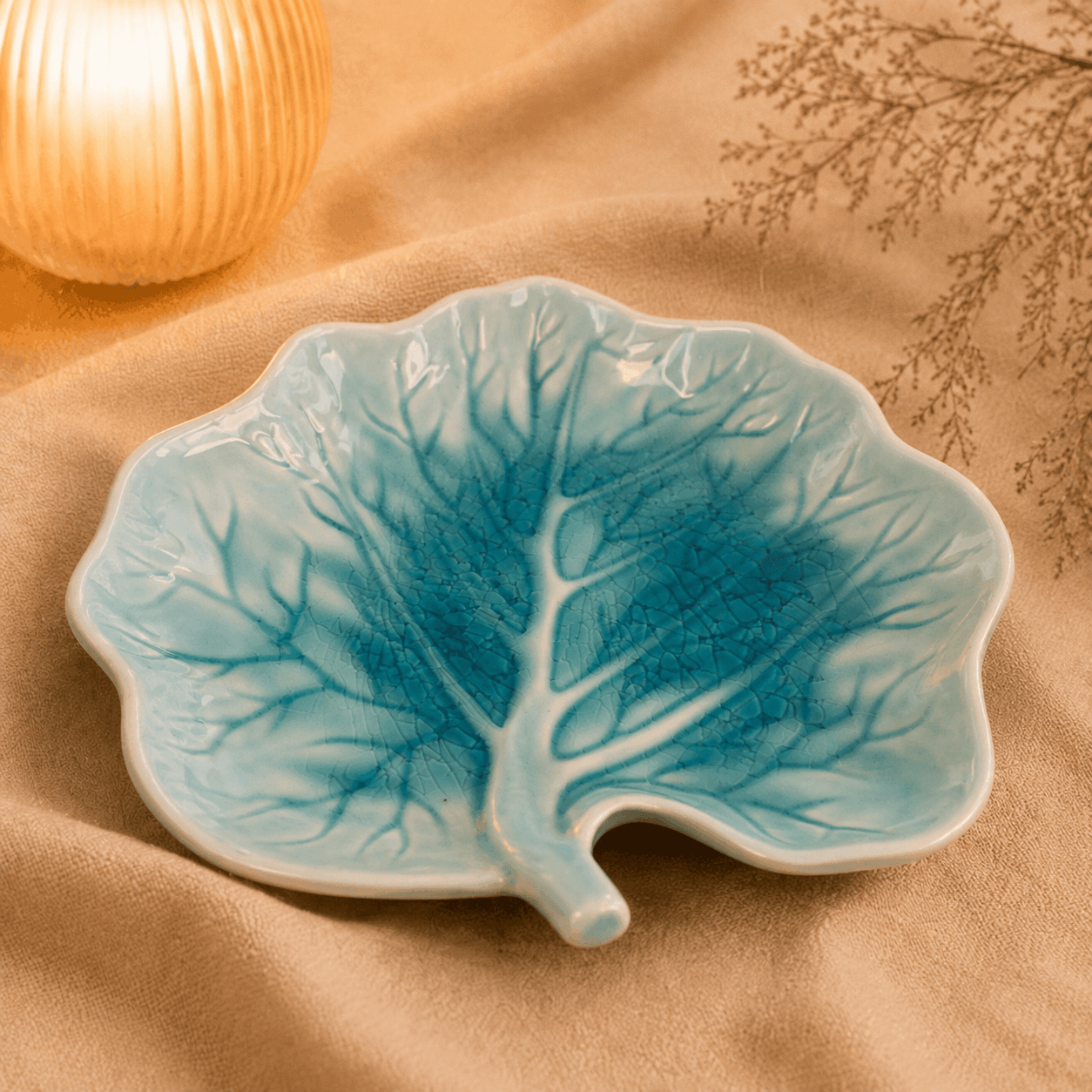 Turquoise serveerbord Lotus van 23,5 cm in bladvorm met sierlijk nervenpatroon, sfeervol gepresenteerd.