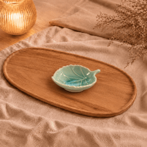 Blauw keramisch bladschaaltje van 10 cm, sfeervol gepresenteerd op een houten schaal met beige textiel en warme verlichting.