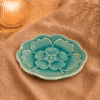Blauw keramieken bloembord van 26 cm met reliëf bloemmotief, sfeervol gepresenteerd op warme stof.