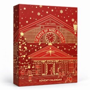 Carnatia 12 Days of Noël Rituals adventskalender in een rode geschenkdoos met goudkleurige kerstillustraties, sneeuwvlokken en een feestelijk stationsgebouw.