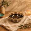 Bruine keramieken lotuskom van 13 cm op een beige linnen doek en houten tafel, sfeervol gecombineerd met olijftakken, een aardewerken vaas en warm kaarslicht.
